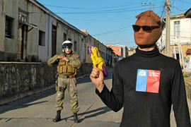 Persona con lentes oscuros y rostro cubierto frente a Carabinero de Chile