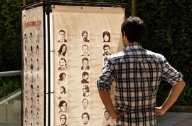 Persona observando la exposición itinerante "Montajes comunicacionales del pasado y del presente"