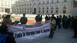 Personas fuera de la Moneda con lienzo "¿Dónde están? Toda la Verdad Toda la Justicia