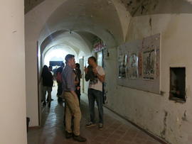Personas observando afiches de la Brigada 40 años en exhibición en Nápoles