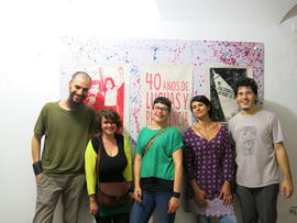 Personas frente a afiches de la Brigada 40 años en exhibición en Nápoles