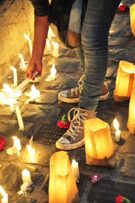 Persona encendiendo vela en frontis de Londres 38 durante conmemoración del 11 de septiembre