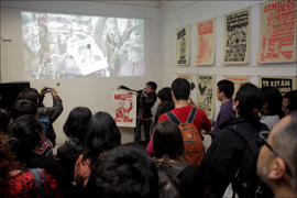 Personas escuchando presentación sobre exposición de afiches
