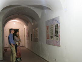 Personas observando afiches de la Brigada 40 años en exhibición en Nápoles