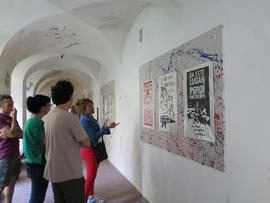 Personas observando afiches de la Brigada 40 años en exhibición en Nápoles